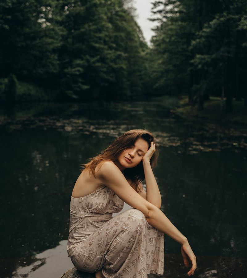 Person sitting peacefully with eyes closed in a calm environment.
