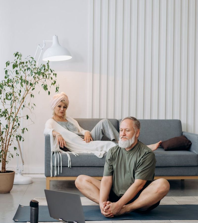 Woman in a relaxed stretching pose in a bright, minimalist room.